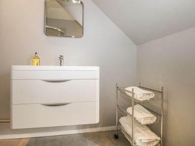 A bathroom sink with a mirror and soap dispenser next to a metal rack with folded towels at Thames Reach in Wallingford