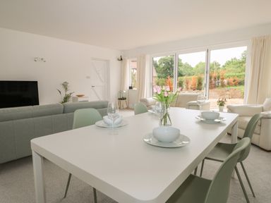 A dining table set with bowls and glasses in a living room with sofas and large windows at Thames Reach in Wallingford