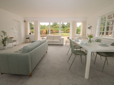 A living room with sofas a dining table with chairs and flowers at Thames Reach in Wallingford