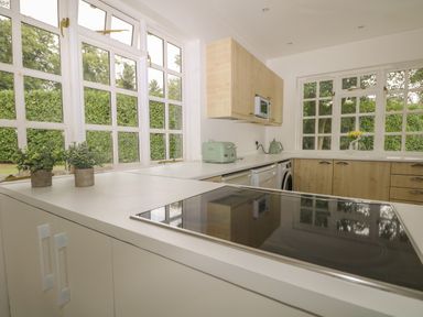 A kitchen with white countertops wooden cabinets appliances and windows showing green foliage at Thames Reach in Wallingford