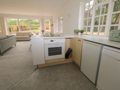 A kitchen with an oven fridge toaster and plants with a living room and sofas visible through large windows at Thames Reach in Wallingford