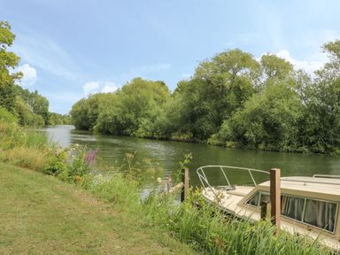 A river with trees on both sides and a boat moored by the riverbank at Thames Reach in Wallingford