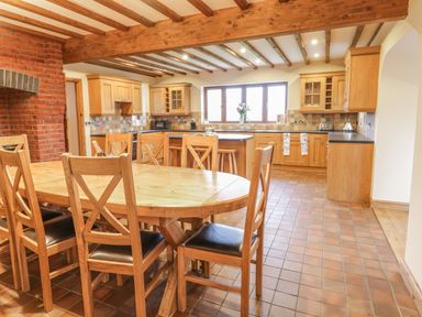 A kitchen with wooden cabinets and a dining table with chairs at Ty Berllan in Caersws