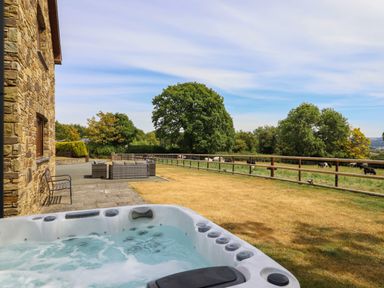 An outdoor area with a hot tub and seating at Ty Berllan in Caersws