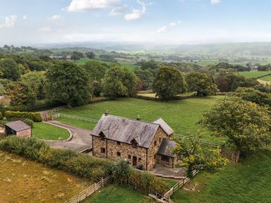 A house surrounded by trees and a field at Ty Berllan in Caersws