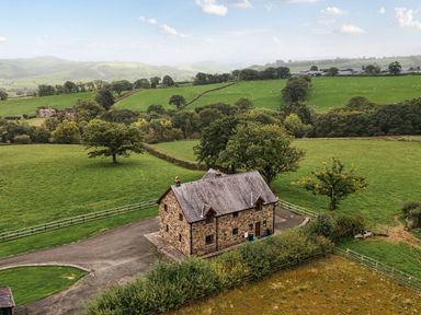 A house surrounded by fields and trees at Ty Berllan in Caersws