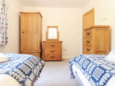 A bedroom with two beds with blue and white blankets and wooden furniture at Ochr Y Garth in Maenan