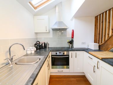 A kitchen with a sink stove oven and wooden stairs at Linden Cottage Ravenstonedale Nr Kirby Stephen