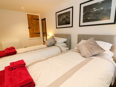 A bedroom with two single beds each with pillows and red towels on top at Linden Cottage in Ravenstonedale Nr Kirby Stephen