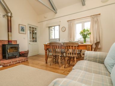 A dining area with a wooden table and chairs a wood burning stove and a sofa at Oreos Cottage in St Agnes
