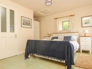 A bedroom with a double bed bedside tables lamps and framed pictures at Oreos Cottage in St Agnes