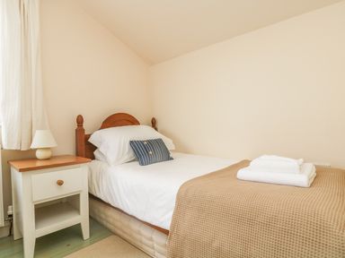 A bedroom with a single bed beside a nightstand with a lamp at Oreos Cottage in St Agnes