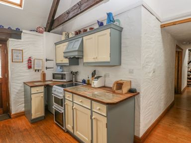 A kitchen with wooden countertops and cream and blue cabinets at Heather Cottage in Rosemarket