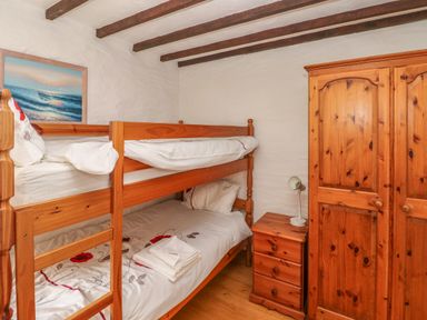 A bedroom with wooden bunk beds wooden wardrobe wooden nightstand and a lamp at Heather Cottage in Rosemarket