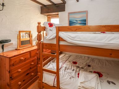 A bedroom with wooden bunk beds and a wooden dresser with a mirror at Heather Cottage in Rosemarket