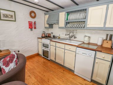 A kitchen with cream and gray cabinets electric stove dishwasher and sink at Cowslip Cottage in Rosemarket