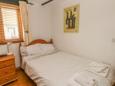 A bedroom with a double bed bedside table and window blinds at Cowslip Cottage in Rosemarket