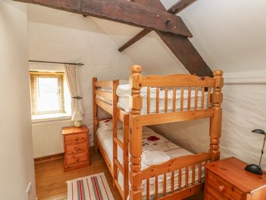 A bedroom with wooden bunk beds two bedside tables and a window at Primose Cottage in Rosemarket
