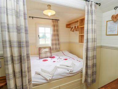 A small bedroom with a bed linens folded towels and a window at Shepherds Hut - The Crook in Rosemarket near Neyland