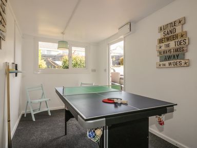 A game room with a table tennis and pool table combo and chairs at Chi An Mor in Porth