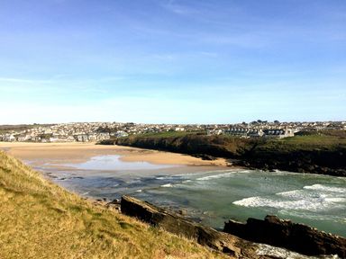 A coastal view with a sandy beach green grassy cliffs and houses on hills at Chi An Mor in Porth