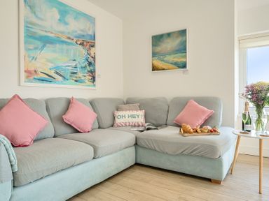 A living room with a sofa and paintings at Chi An Mor in Porth