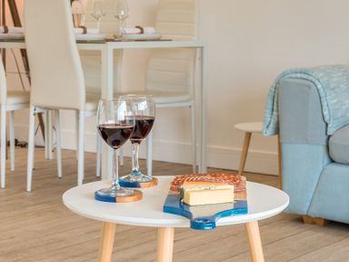 A living room with red wine and cheese on a low table at Chi An Mor Porth