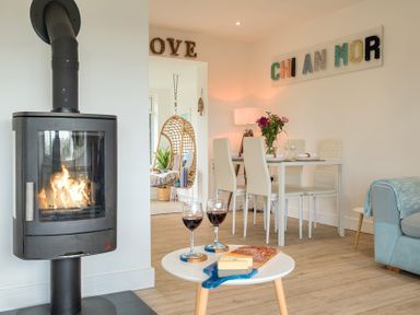 A living room with a wood stove and dining table at Chi An Mor in Porth