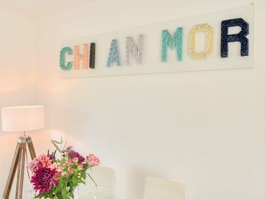 A dining room with a lamp and flowers at Chi An Mor in Porth