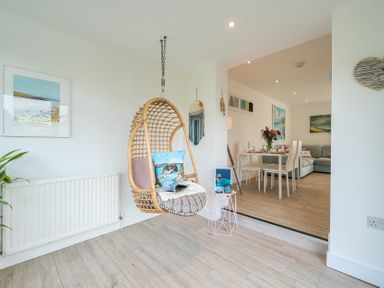 A living room with a hanging chair and dining area at Chi An Mor in Porth