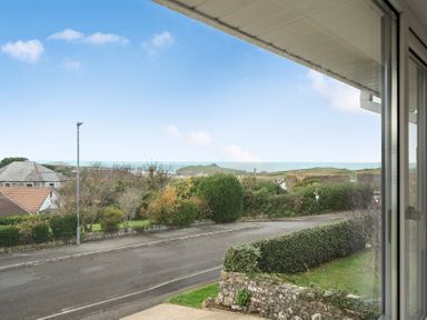 A view of houses and ocean from a window at Chi An Mor in Porth