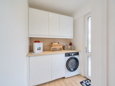 A utility room with cabinets and a washing machine at Chi An Mor Porth