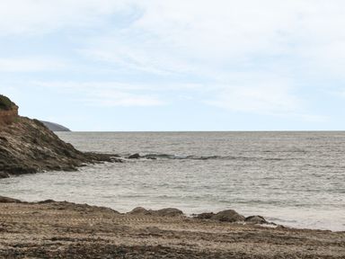 A rocky beach with tire tracks in the sand and ocean waves at Phenests in Falmouth