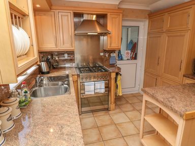 A kitchen with wooden cabinets a stainless steel stove and oven a double sink and a countertop island at Phenests in Falmouth