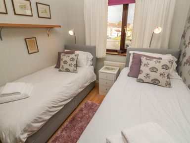 A bedroom with two single beds pillows bedside table and window at Phenests in Falmouth