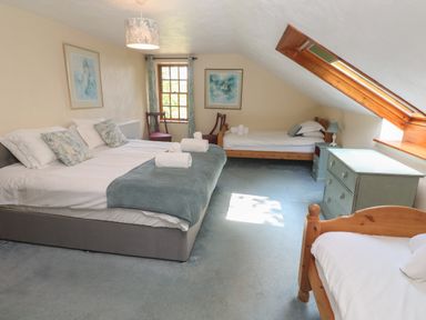 A bedroom with three beds two chairs a dresser and a skylight window at Beggars Roost in Penhallow