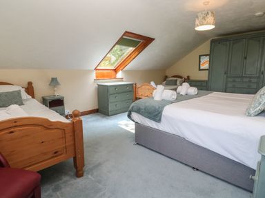 A bedroom with multiple beds a skylight and green furniture at Beggars Roost in Penhallow