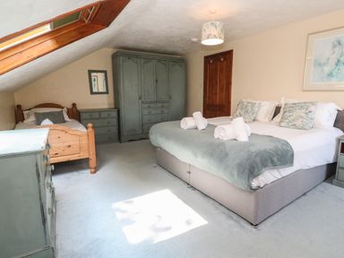 A bedroom with a double bed and a single bed under a sloped ceiling at Beggars Roost in Penhallow