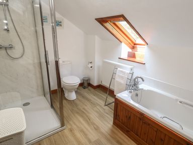 A bathroom with a shower, toilet, bathtub, towel rack and skylight window at Beggars Roost in Penhallow