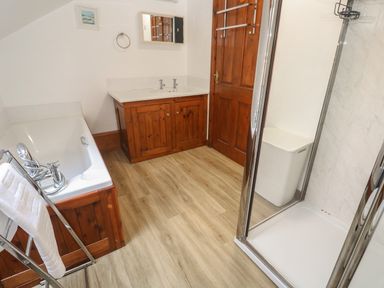 A bathroom with a bathtub towel rack sink cabinet wooden door and shower at Beggars Roost Penhallow