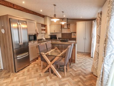 A kitchen with stainless steel refrigerator glass dining table and four chairs at Avonal Lodge in Dunning