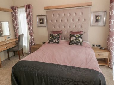 A bedroom with a double bed a desk a chair and two nightstands at Avonal Lodge 24 in Dunning