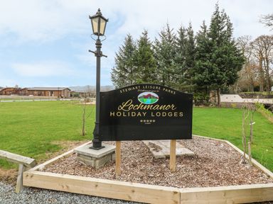 A sign for Lochmanor Holiday Lodges with a lamp post and trees in the background at Avonal Lodge 24 in Dunning