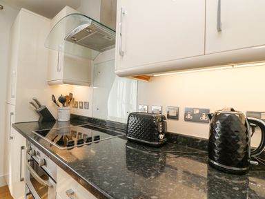 A kitchen countertop with a stove a toaster a kettle and kitchen utensils at Admirals Quarter Apartment 4 Weymouth