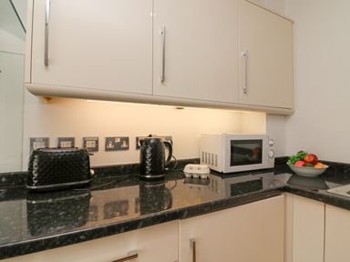 A kitchen counter with a toaster kettle microwave bowl of fruit and an egg container at Admirals Quarter Apartment 4 in Weymouth