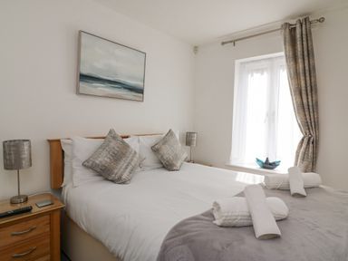 A bedroom with a double bed two pillows bedside tables lamps and rolled towels at Admirals Quarter Apartment 4 in Weymouth