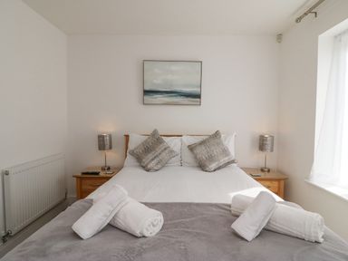 A bedroom with a bed with grey pillows and lamps on wooden bedside tables at Admiral's Quarter Apartment 4 in Weymouth