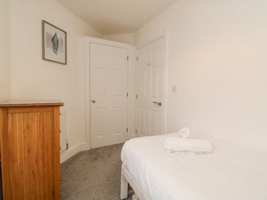 A bedroom with a wooden chest of drawers a bed with folded towels and two white doors at Admirals Quarter Apartment 4 in Weymouth