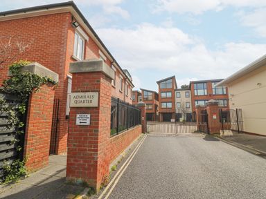 Entrance to a gated residential complex with brick pillars and modern brick buildings in the background at Admirals Quarter Apartment 4 in Weymouth