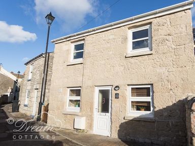 A stone cottage with white framed windows and a white door on a narrow street at Ammonite Cottage Fortuneswell Portland